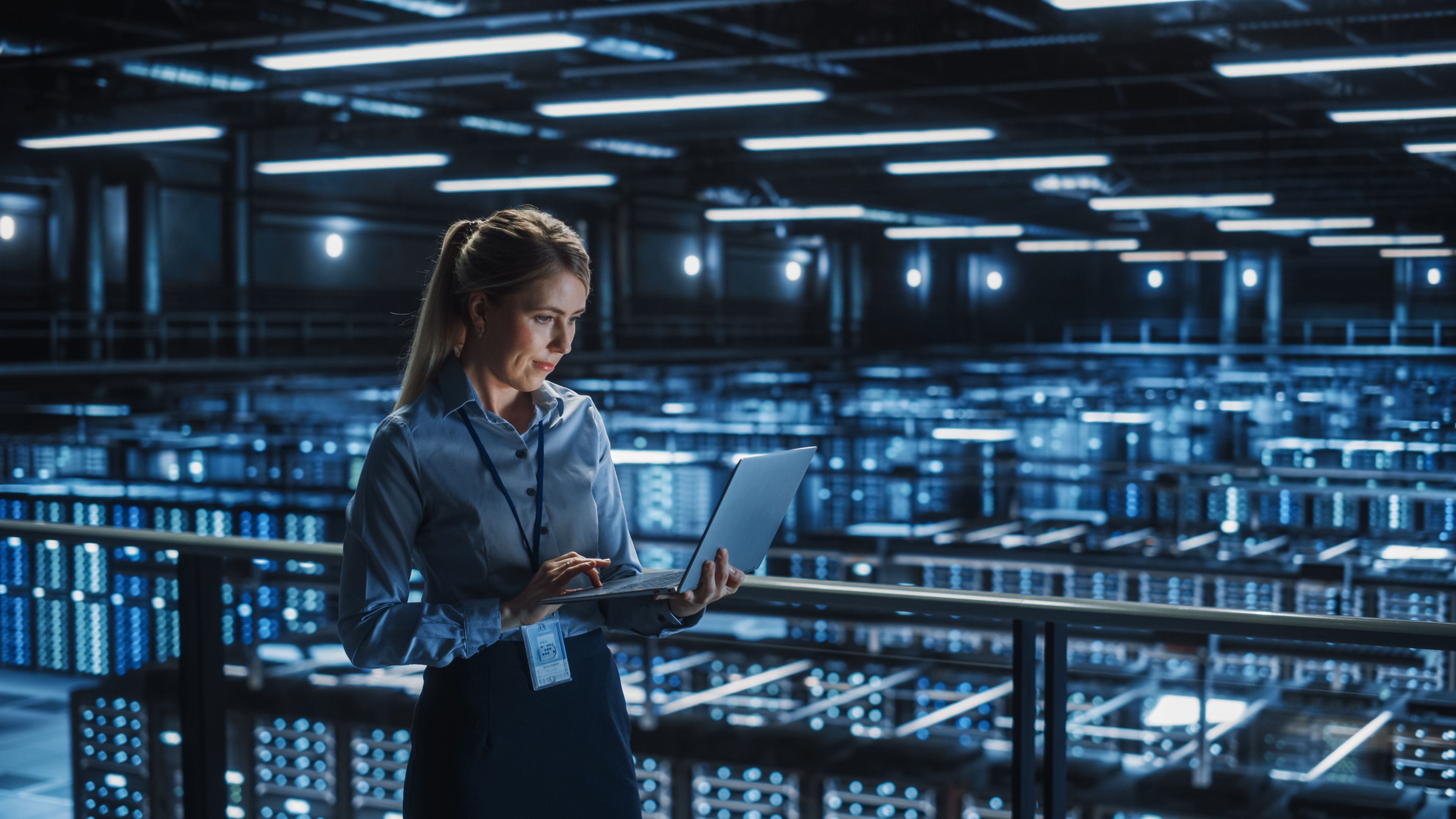 A woman with a computer works in a data center. 